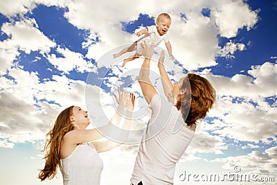 Happy family throws up baby boy against blue sky