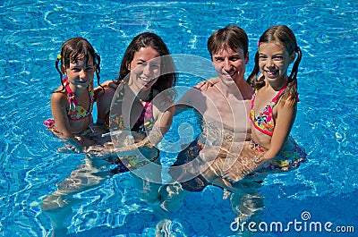 Happy family with two kids in swimming pool