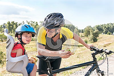 Happy father and son is eating lunch (snack) during bicycle ride