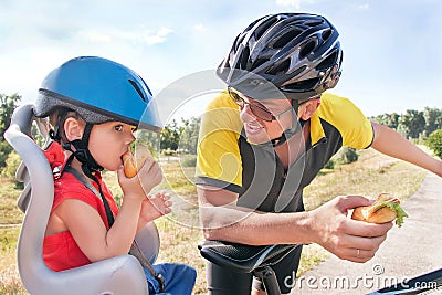 Happy father and son is eating lunch (snack) during bicycle ride