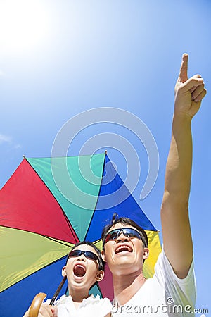 Happy father and son holding a umbrella with blue sky