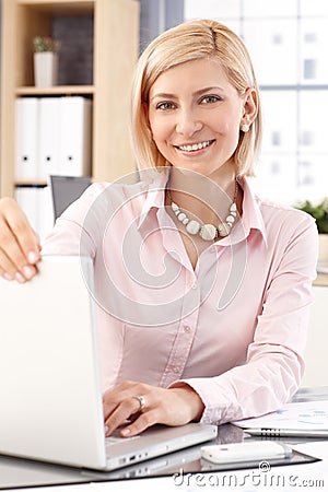 Happy female office worker with laptop computer