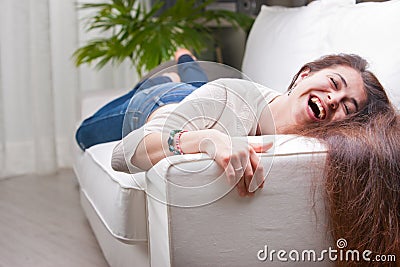 Happy girl laughing on a sofa