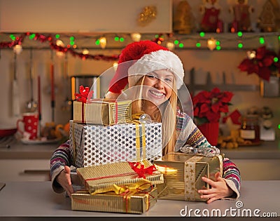 Happy girl in santa hat with stack of christmas present boxes