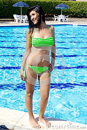 Happy girl in swimming pool in the summer posing