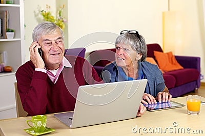 Happy grandfather talking on the phone with son at home