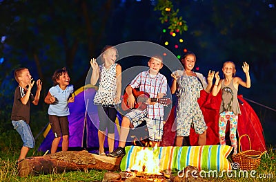 Happy kids dancing around campfire