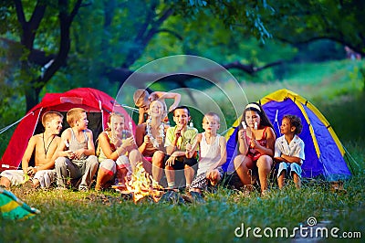 Happy kids roasting marshmallows on campfire