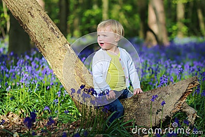 Happy little girl playing in bluebells forest