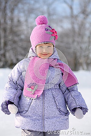 Happy little girl wearing in pink scarf and hat smiles