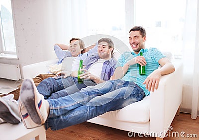 Happy male friends with beer watching tv at home