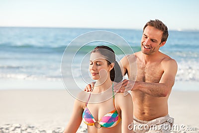 Happy man applying sun cream on his girlfriend