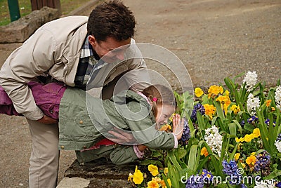 Happy man holding a child above the flower bed