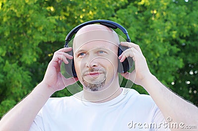 Happy man listening music outdoors in wireless headset