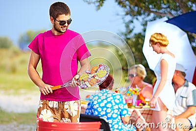 Happy man prepares food on the grill, family picnic