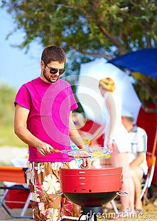 Happy man prepares food on the grill, family picnic