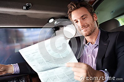 Happy man reading news in luxury car