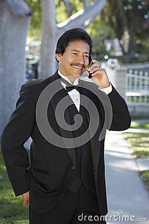 Happy Man In tuxedo Using Cell Phone At Quinceanera