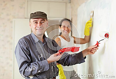 Happy man and woman paints wall at apartment