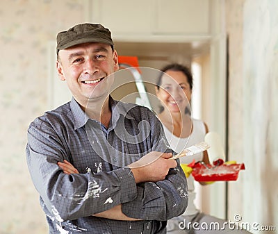 Happy man and woman paints wall at home
