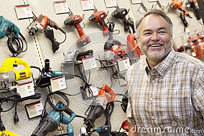 Happy mature hardware store owner looking away