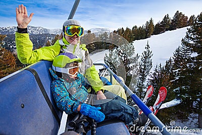Happy mom and boy in ski masks seat on elevator