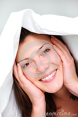 A picture of a happy young woman covered by a white bedding. - happy-morning-23829389