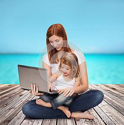 Happy mother with adorable little girl and laptop