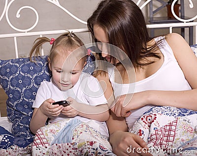 Happy mother with daughter in bed watching tv