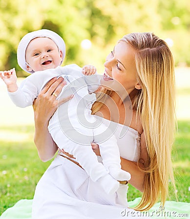 Happy mother with little baby sitting on blanket