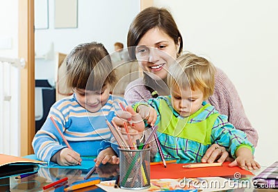 Happy mother and two children sketching on paper