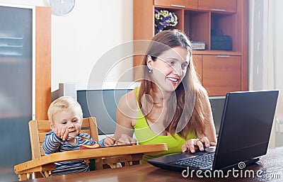 Happy mother working with laptop and baby