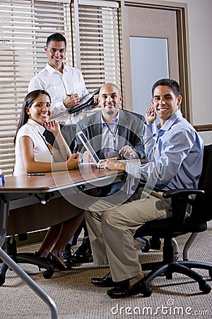 Happy office workers meeting at table in boardroom