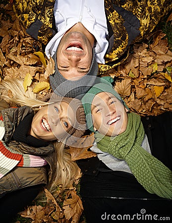 Happy people in autumn park laying among leaves