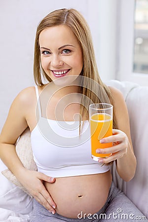 Happy pregnant woman with fresh orange juice