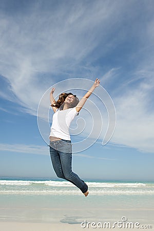 Happy pretty woman jumping for joy at beach