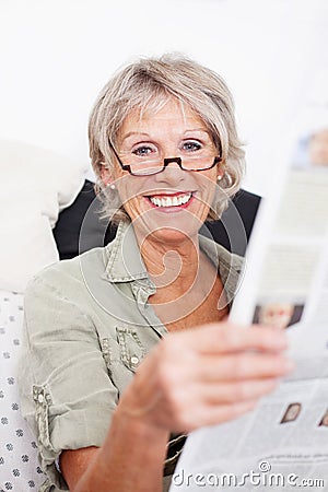 Happy retired woman reading the newspaper