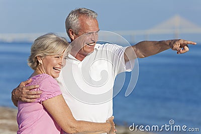 Happy Senior Couple Walking Pointing on Beach