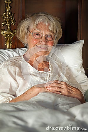 Happy senior lady relaxing in bed