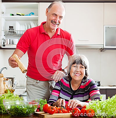 Happy senior man in red and woman cooking together