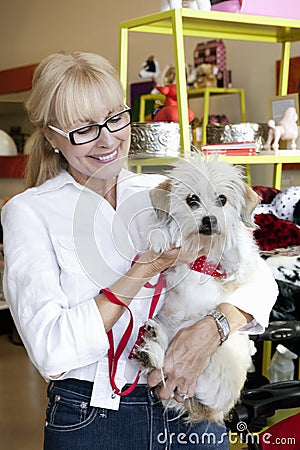 Happy senior woman carrying dog in pet shop