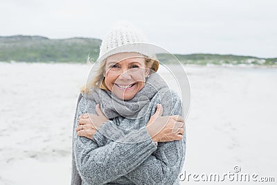 Happy senior woman feeling cold at beach