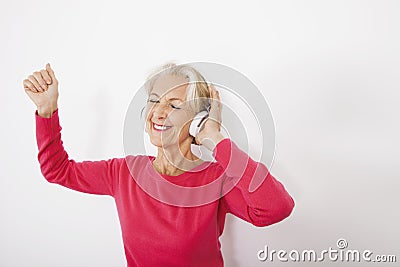 Happy senior woman listening music over white background