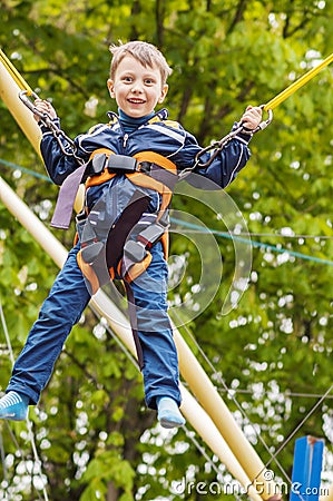 Happy smiling boy is jumping on trampoline