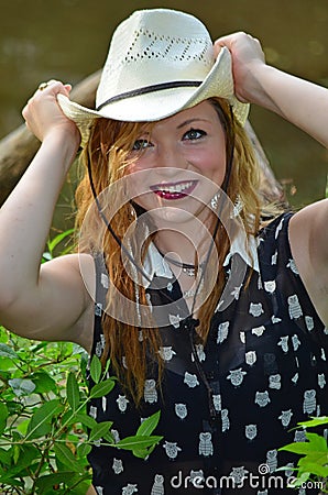 Happy Smiling Cowgirl Putting on Her Cowboy Hat