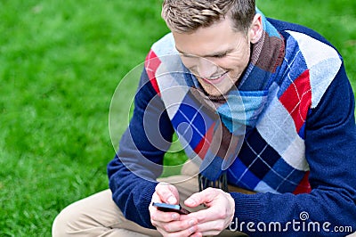 Happy smiling man using mobile phone on park