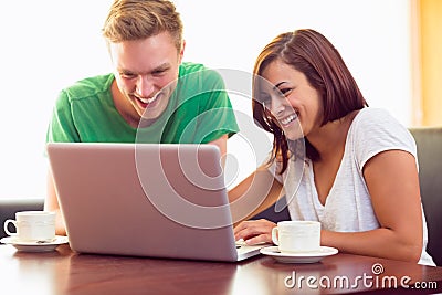 Happy students using laptop while having coffee at coffee shop