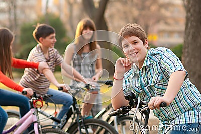 Happy teenage boy on bicycle with friends