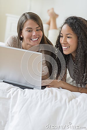 Happy Teenage Girls Using Laptop In Bed