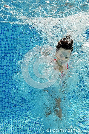 Happy underwater child jumps to swimming pool